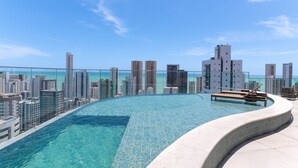 Une piscine à débordement située sur le toit, offrant une vue sur la ville et entourée de gratte-ciel.