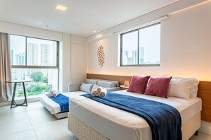 Une chambre d’hôtel moderne avec un grand lit, un canapé, une petite table et une vue sur la ville.