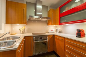 Een moderne keuken met roestvrijstalen apparatuur, houten kastjes en een raam met een rode omlijsting.