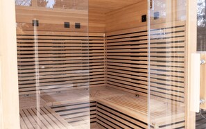 Sauna, jossa on puinen sisustus ja lasiseinät.