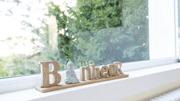 Un rebord de fenêtre orné de lettres en bois formant le mot « Bonjour » et d’une petite statue de Bouddha en pierre.