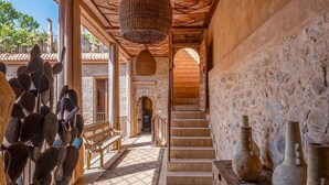 Un interior amplio con una escalera de madera, una escultura de cactus y jarrones tradicionales.