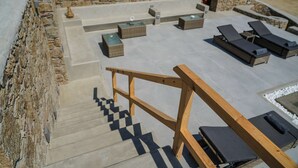 En tagterrasse med udendørs møbler, en trætrap og stenvægge.