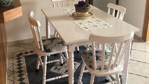 Un coin repas avec une table blanche, des chaises à motifs floraux et un tapis à dessins.