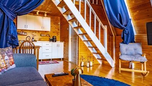 Un dormitorio tipo loft acogedor con una escalera de madera, un sofá, una mesa de centro y una silla.