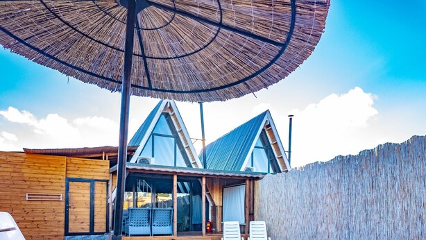 Una casa moderna con piscina, terraza de madera y sillones de descanso.