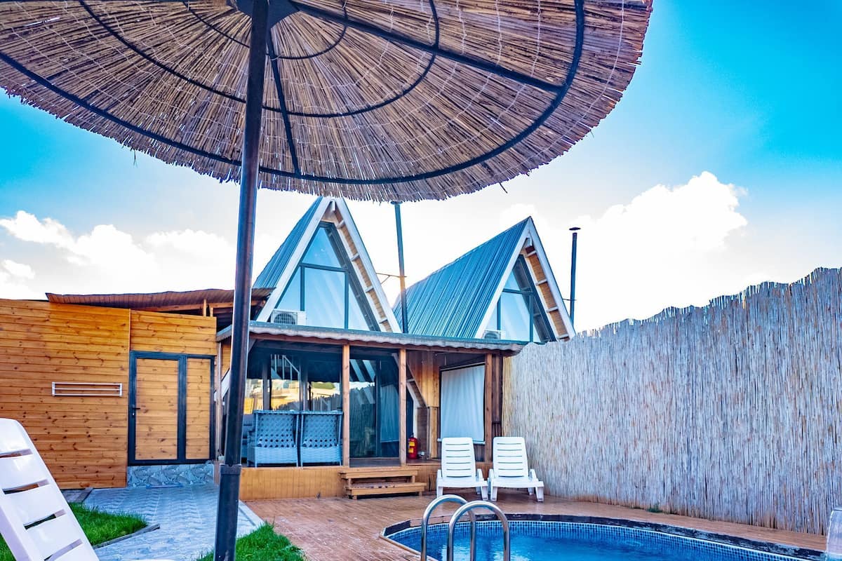 Una casa moderna con piscina, terraza de madera y sillones de descanso.