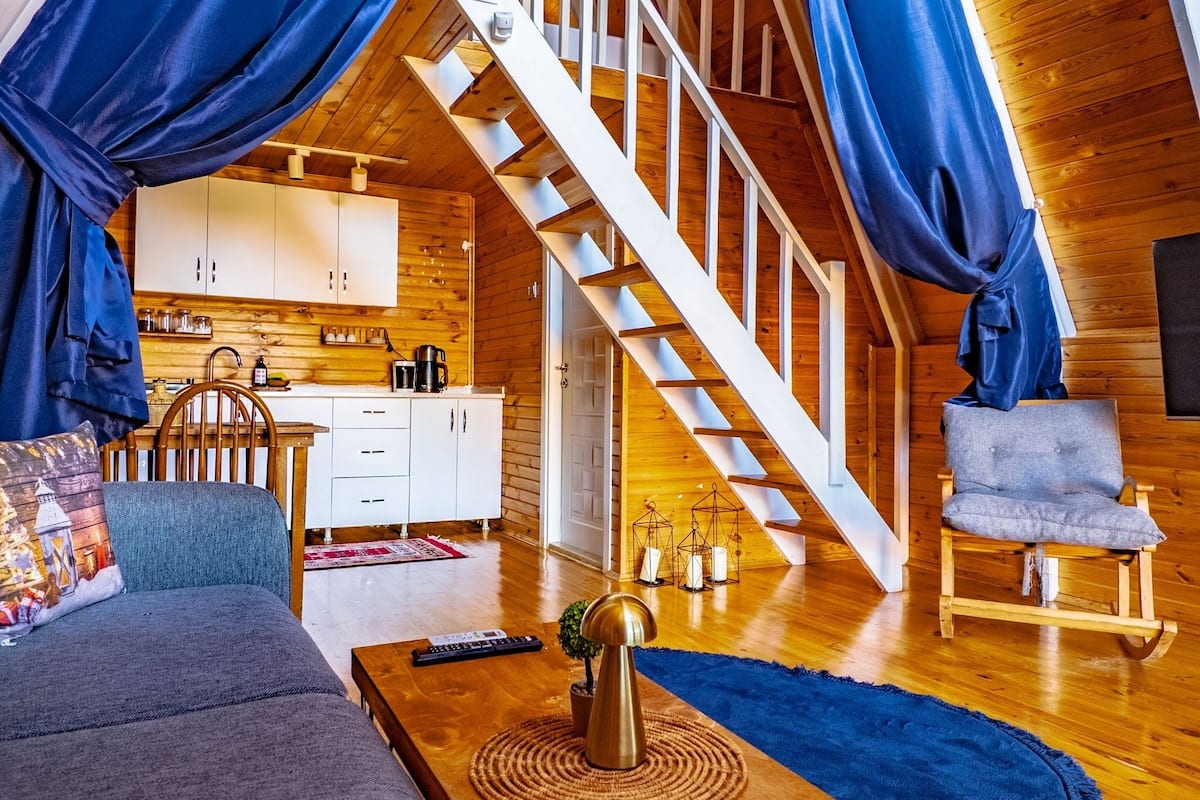 Un acogedor loft con escalera de madera, un sofá, una mesa de centro y una silla.