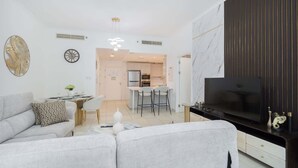 Un salon moderne avec un canapé, un téléviseur et un coin repas comprenant des chaises et une table.