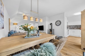 A modern kitchen with white cabinets, a wooden countertop, and a built-in stove. - Schleiglück -Beach chair, infrared heat cabin, fireplace, balcony, parking space (Olpenitz)