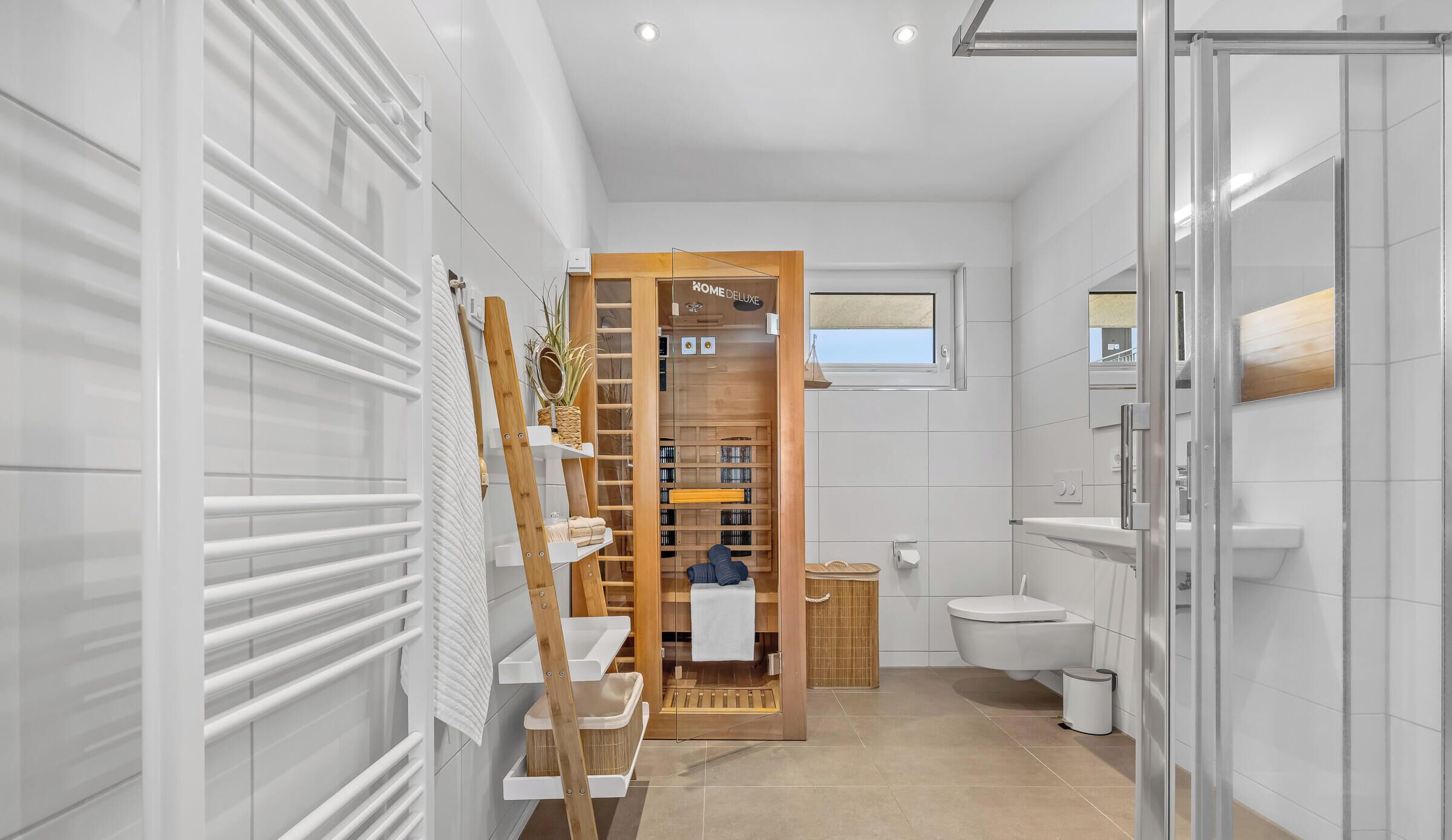 A modern bathroom with a glass shower enclosure, a wooden vanity, and a built-in storage unit.