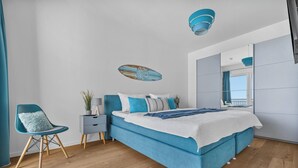 Une chambre à coucher moderne avec un grand lit, une chaise, une table de chevet et un miroir.