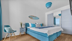 Ein modernes Schlafzimmer mit einem großen Bett, einem Sessel, einem Nachttisch und einem Spiegel.