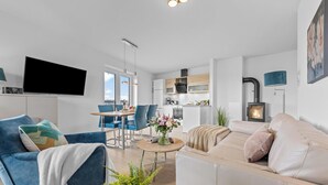 Ein modernes Wohnzimmer mit einer Couch, Sesseln, einem Fernseher und einem Kamin.