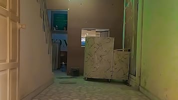 Un pasillo con suelo de baldosas, una escalera y una puerta a la izquierda.
