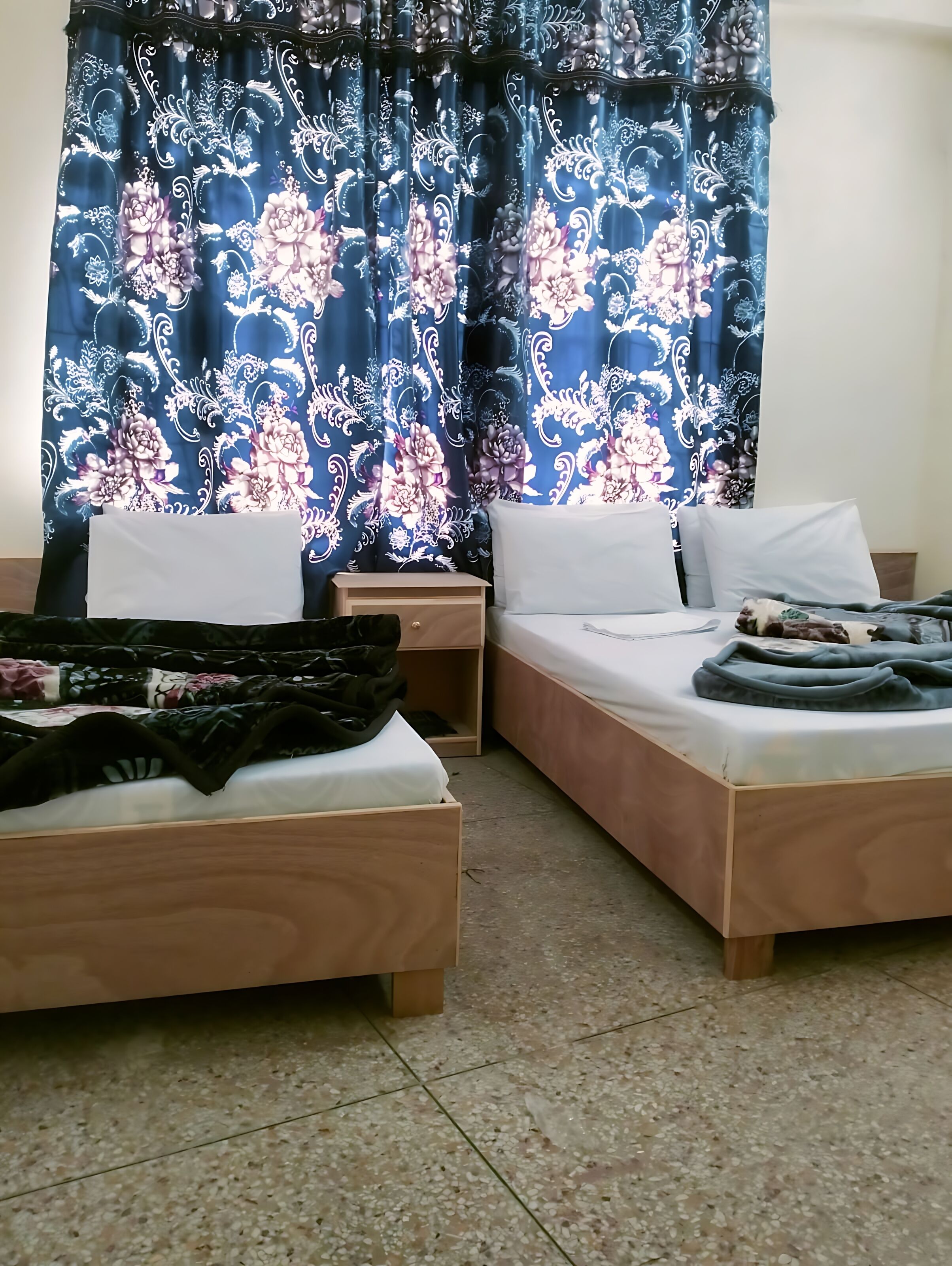 A room with two wooden beds, a nightstand, and a wardrobe.