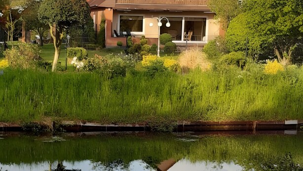Una casa con techo rojo, un balcón y su reflejo en el agua.