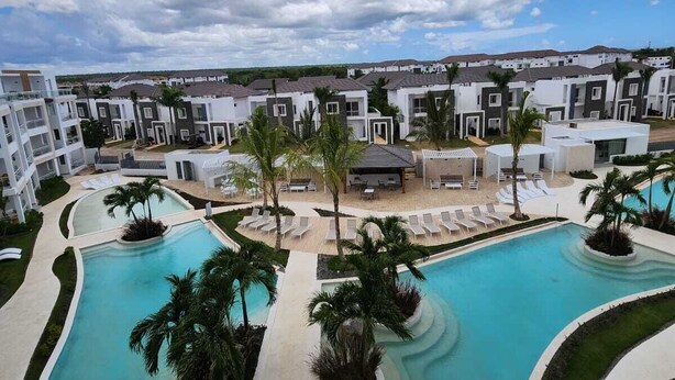 Un resort con una grande piscina centrale, diversi edifici e cielo sereno.