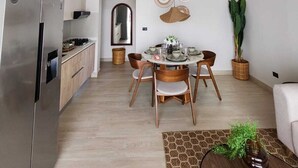 Una cucina moderna con frigorifero in acciaio inossidabile, travi a cassetto in legno e zona pranzo con tavolo rotondo e sedie.
