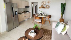 Una cucina moderna con elettrodomestici in acciaio inossidabile, un'area pranzo con un tavolo rotondo e sedie, e un soggiorno con divano e tavolino.