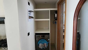 A narrow hallway with a washing machine, a wooden door, and a tiled wall. - Sunshine Caribbean Apartment (Dominicus)