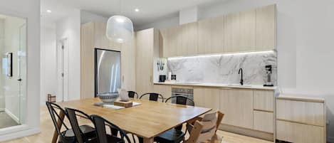 A modern kitchen with a marble countertop, wooden cabinets, and a dining area with a wooden table and chairs.