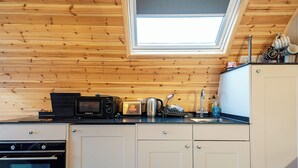 A kitchen with wooden paneling, a skylight, a microwave, toaster, sink, and cabinets. - 1 bedroom accommodation in Millom (Millom)