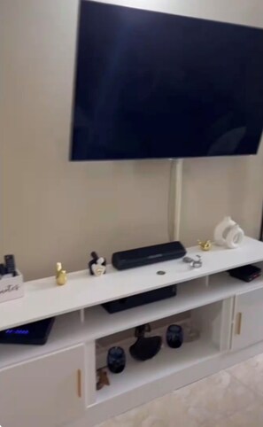 A white entertainment unit with a flat-screen TV mounted above it. - Island Living 2Bedroom  Bungalow in Montego Bay with AC, Hot Water & WiFi (Montego Bay)
