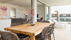 Zona pranzo moderna con tavolo in legno, sedie in vimini e un vaso.