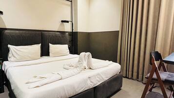 A hotel room with a large bed, a bedside table, a chair, and a curtain.