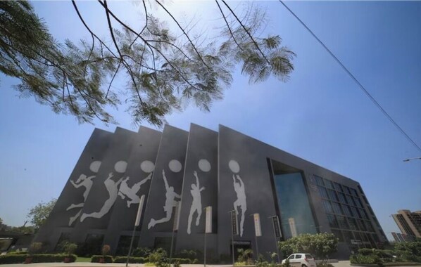 A modern building with a unique facade featuring large white silhouettes of basketball players in various poses. - Ibiza Hotel (Ahmedabad)