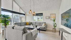 A spacious living room with a sectional sofa, a coffee table, and a large window providing natural light. - VillaVilla 547 - Hostrup Strand, Limfjorden (Spøttrup)
