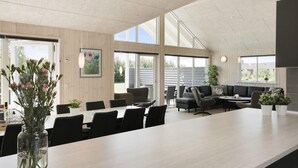 A modern kitchen with a large island, dining area, and seating space.