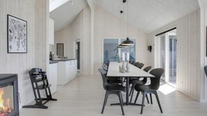 Une cuisine moderne dotée d’un îlot central, d’un coin repas avec une longue table et des chaises, et d’une cheminée.