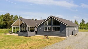 A two-story house with a covered patio and a gravel driveway.