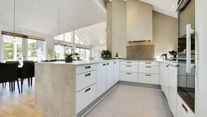 Eine moderne Küche mit weißen Schränken, einer großen Kochinsel und einem Essbereich mit Ausblick.