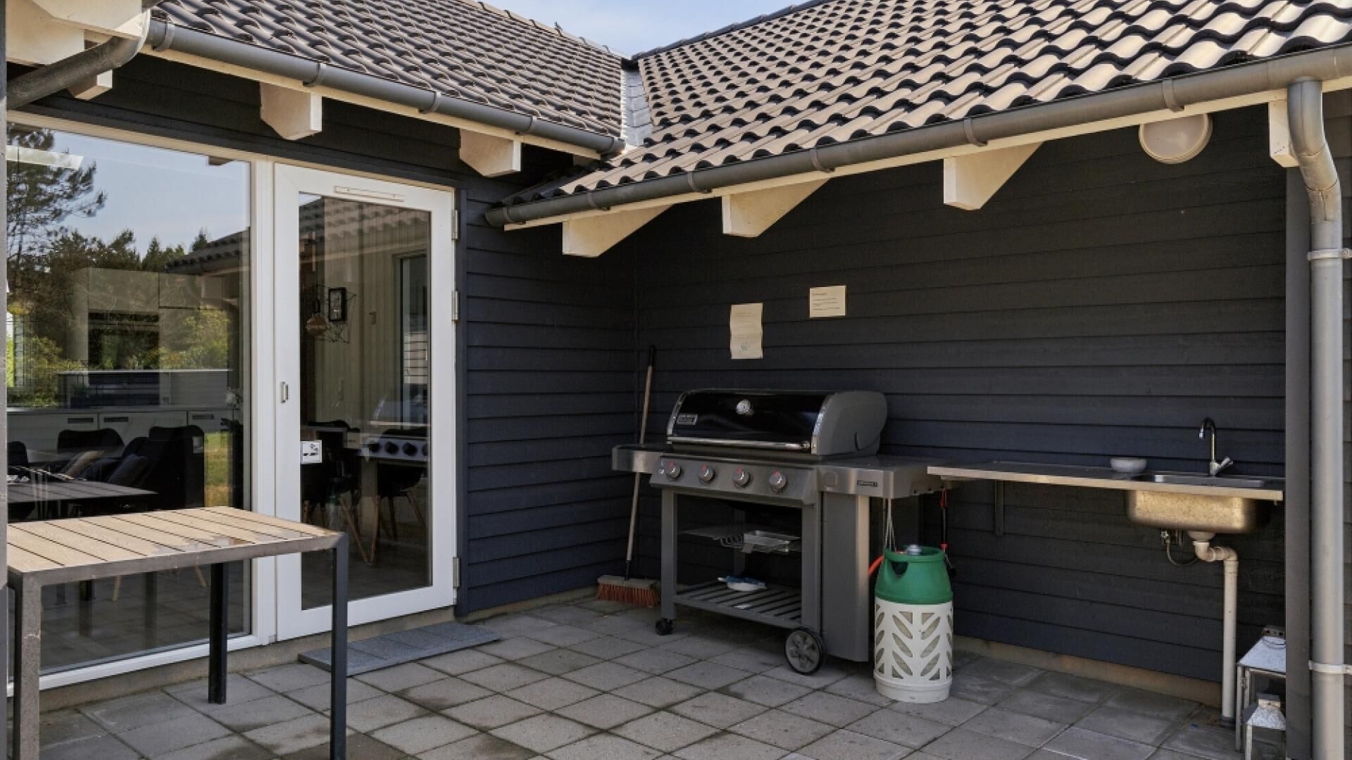An outdoor patio with a grill, a sink, and a table.