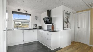 Eine moderne Küche mit weißen Schränken, einer schwarzen Arbeitsplatte, einer Kaffeemaschine und einer Uhr an der Wand.