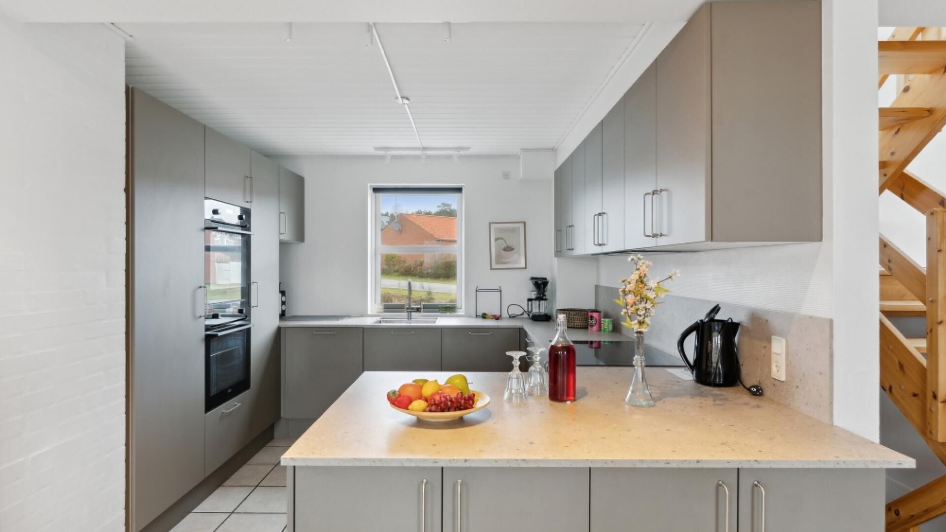 A modern kitchen with grey cabinets, a large island, and a view of the outdoors.