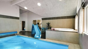 Ein Innenpool mit Rutsche, Whirlpool und Sitzbereich mit Stühlen.