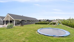 Il s’agit d’une propriété résidentielle comprenant une maison, un trampoline et un ensemble de jeux en bois avec balançoire.
