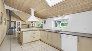 Une cuisine moderne avec des meubles en bois, un îlot central, une fenêtre et un lave-vaisselle encastré.