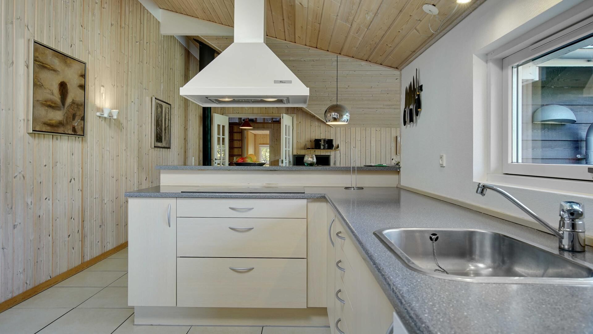 Cocina moderna con isla central, pileta de acero inoxidable y techo de madera.
