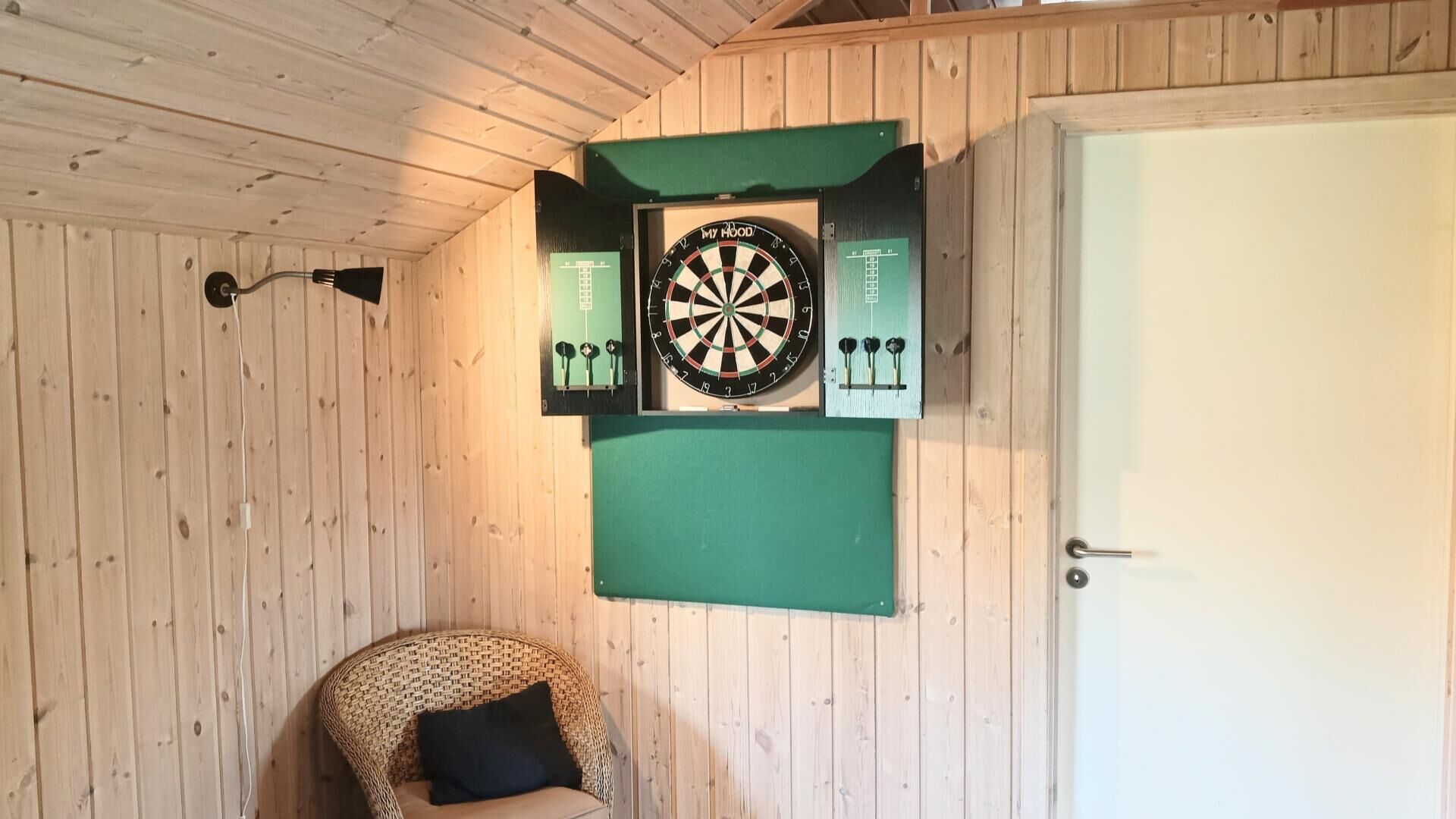Una habitación con paredes de madera, un dardo y una puerta.