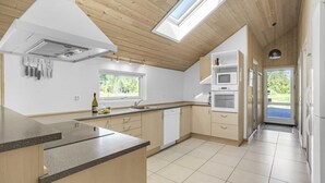 Une cuisine moderne dotée d’un grand îlot central, d’un four encastré et d’une lucarne.