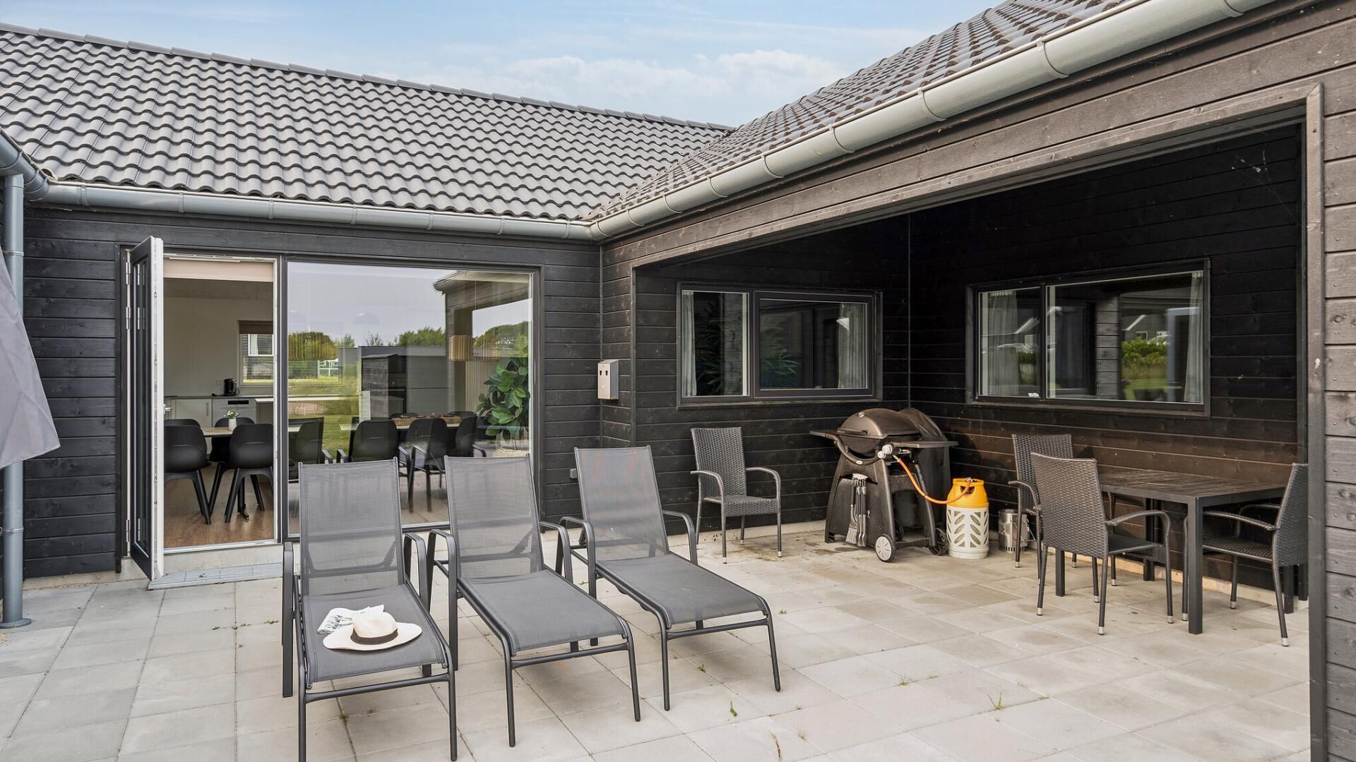 An outdoor patio with a grill, dining table, and chairs.