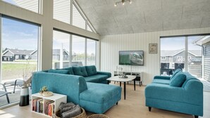 Tilava olohuone, jossa on turkoosinsiniset sohvat, sohvapöytä ja seinälle asennettu televisio.