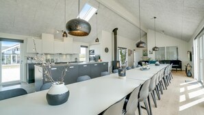 Moderni keittiö, jossa on pitkä keittiösaareke, integroidut kodinkoneet ja riippuvalaisimet.