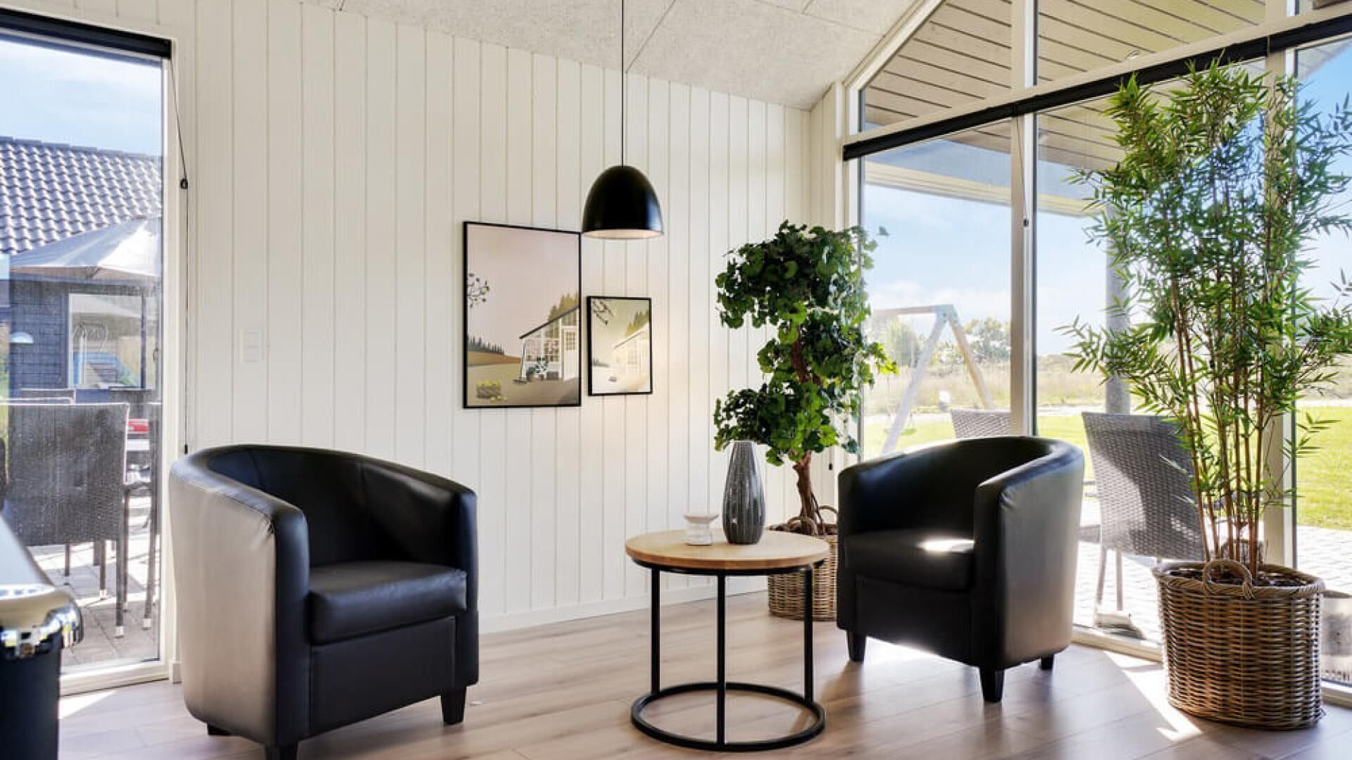 A modern room with two black leather chairs, a small round table, and a potted plant.
