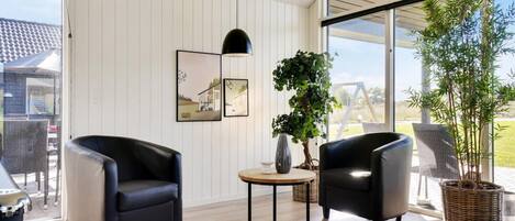 A modern room with two black leather chairs, a small round table, and a potted plant.